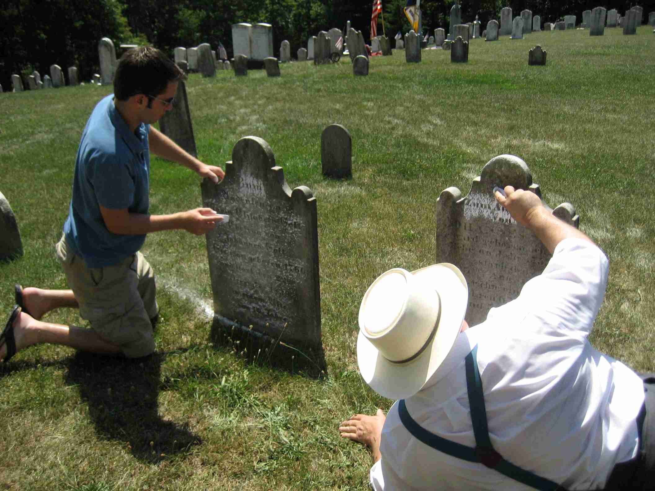 John Sinks using chalk to read a grave marker.